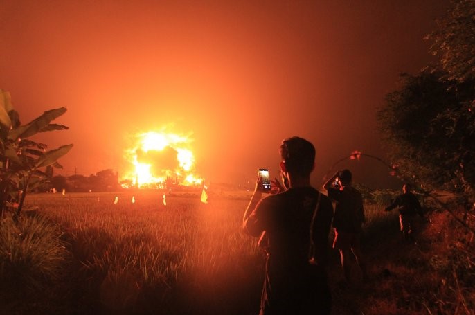 Sejumlah warga sedang mengambil gambar kebakaran kilang minyak di Balongan, Indramayu, Jawa Barat. (Foto: Ant)
