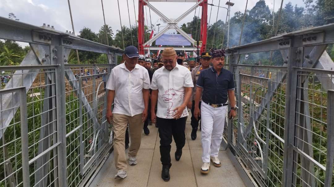 Sumail Abdullah (tengah) didampingi Camat Kalipuro, Astorik (kanan), melihat jembatan gantung yang baru diresmikan (foto: Muh Hujaini/Ngopibareng.id)