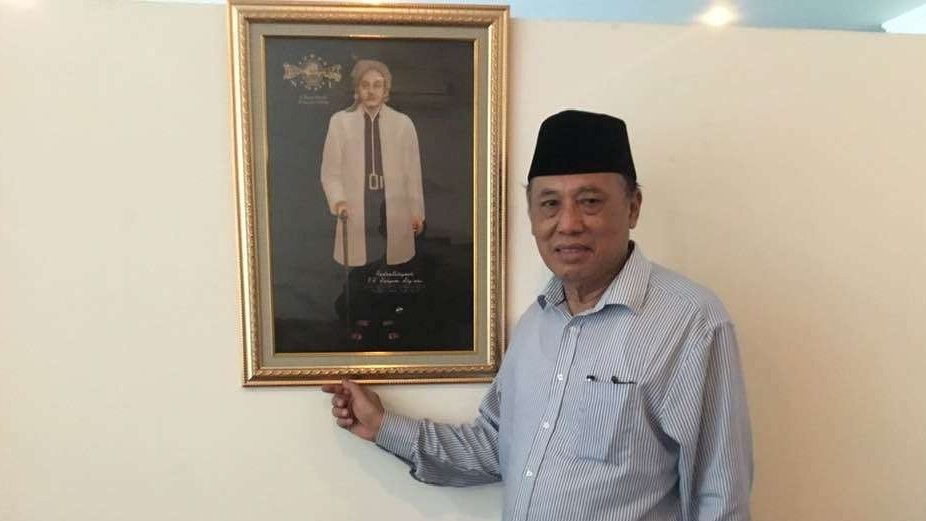 As'ad Said Ali memegang foto KH M. Hasyim Asyari di kantornya di Jakarta. (Foto: dok/ngopibareng.id)