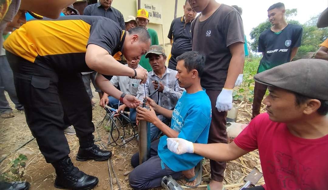 Kapolresta Banyuwangi, Kombespol Nanang Haryono membantu memasang alat pompa air yang akan dipasang di sumur bor (foto: Muh Hujaini/Ngopibareng.id)(
