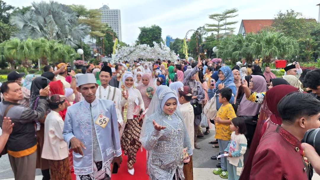 Prosesi kirab para pasangan suami-istri yang akan mengikuti prosesi resepsi nikah massal, yang diselenggarakan oleh Pemerintah Kota Surabaya, Selasa 2 Juli 2024. (Foto: Julianus Palermo/Ngopibareng.id)